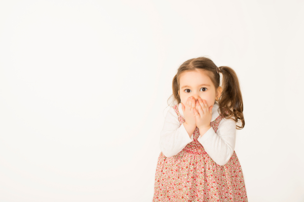 Little girl with her hands over her mouth 