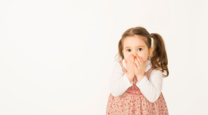 Little girl with her hands over her mouth