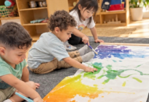 Image: Three children painting on butcher paper